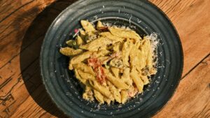 Cooked penne pasta on black plate